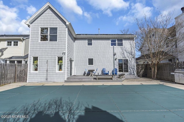 rear view of property with fence and a fenced in pool