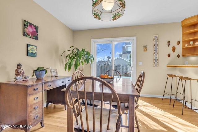 dining space with light wood finished floors and baseboards