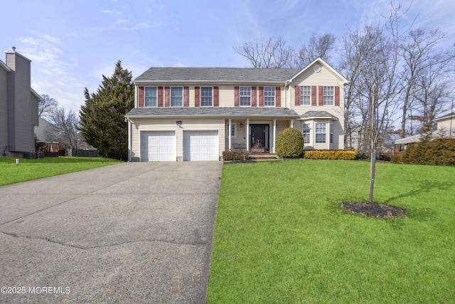 traditional-style home featuring a garage, aphalt driveway, and a front yard