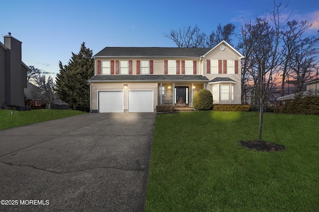 traditional home with concrete driveway, an attached garage, and a front yard