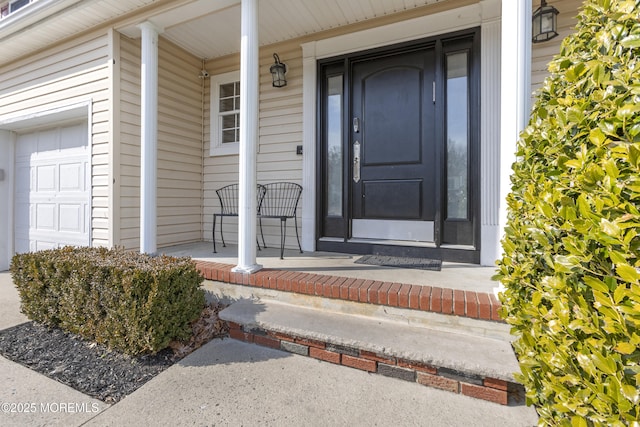 view of exterior entry with covered porch and an attached garage