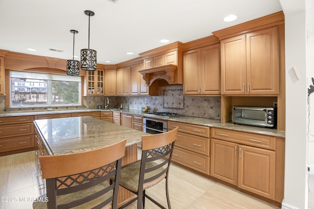 kitchen featuring tasteful backsplash, a toaster, light stone counters, a kitchen breakfast bar, and stainless steel appliances