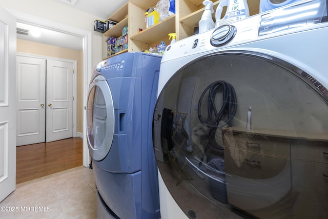 clothes washing area featuring washer and dryer, laundry area, visible vents, and light tile patterned floors