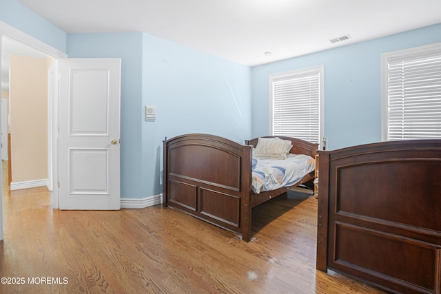 bedroom featuring visible vents, light wood-style flooring, and baseboards