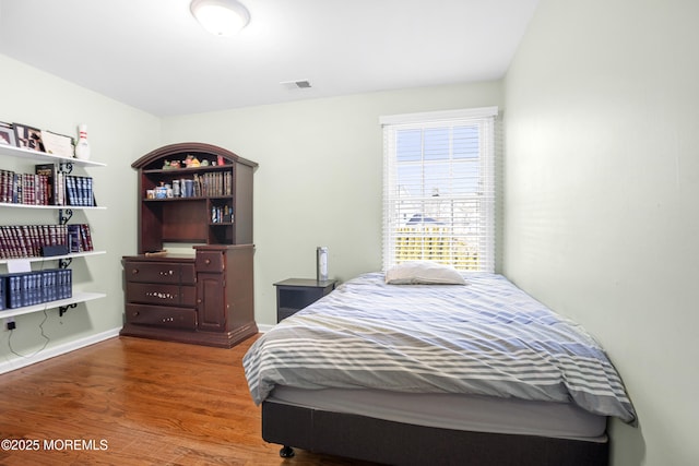 bedroom featuring visible vents, baseboards, and wood finished floors