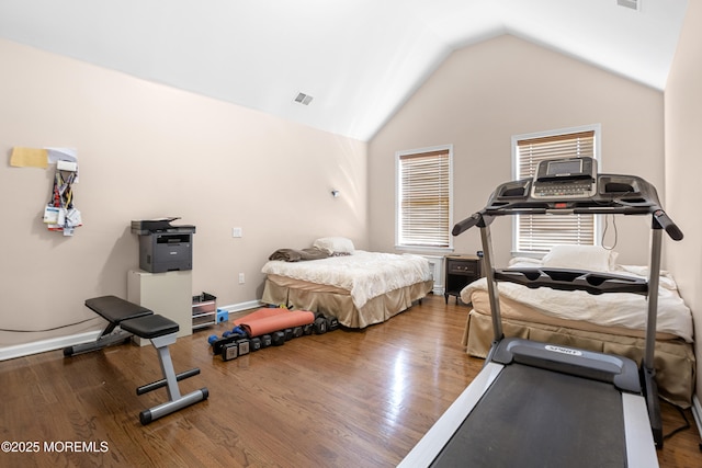 workout room featuring lofted ceiling, visible vents, baseboards, and wood finished floors