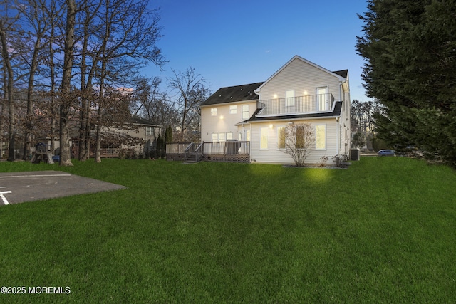 back of property featuring central air condition unit, a wooden deck, and a yard