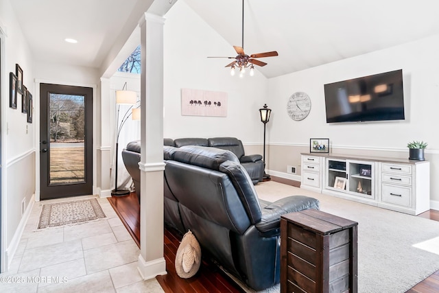 living room featuring baseboards, a ceiling fan, vaulted ceiling, ornate columns, and light tile patterned flooring