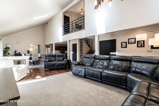 carpeted living area featuring stairs, high vaulted ceiling, a notable chandelier, and wood finished floors