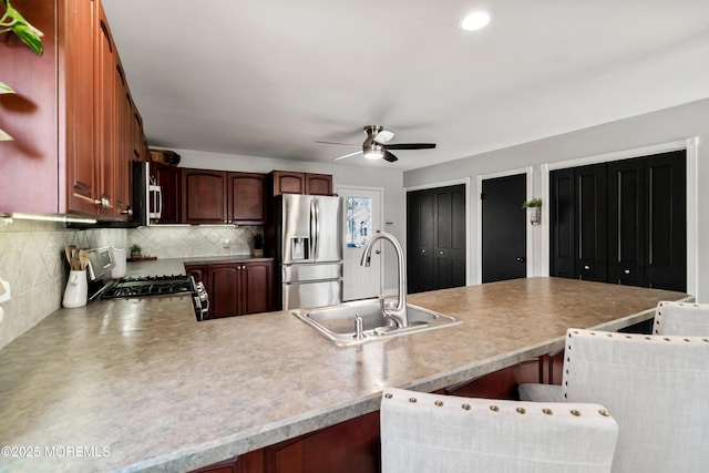 kitchen featuring stainless steel appliances, backsplash, a sink, a peninsula, and a kitchen breakfast bar