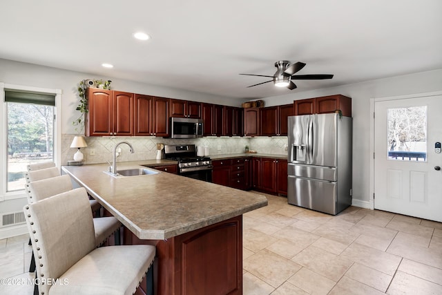 kitchen featuring visible vents, a peninsula, a sink, stainless steel appliances, and backsplash