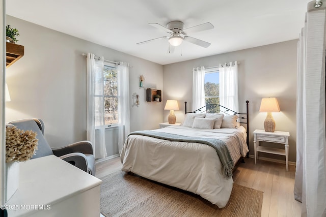 bedroom with light wood-style floors, ceiling fan, and baseboards