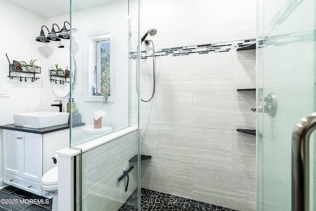 bathroom featuring toilet, a stall shower, and vanity