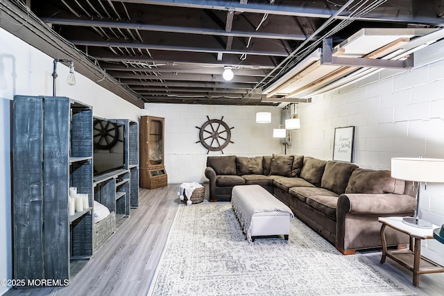 living area with concrete block wall and wood finished floors