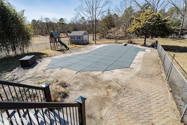 view of swimming pool with a fenced in pool, a patio, an outbuilding, fence, and a playground