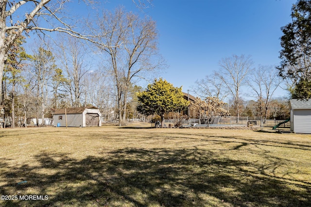 view of yard featuring a storage shed, fence, and an outdoor structure