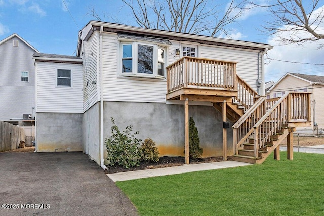 view of front facade featuring fence, stairway, a front lawn, and a wooden deck