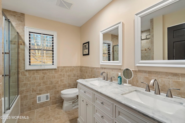 full bath with tile walls, visible vents, and a sink