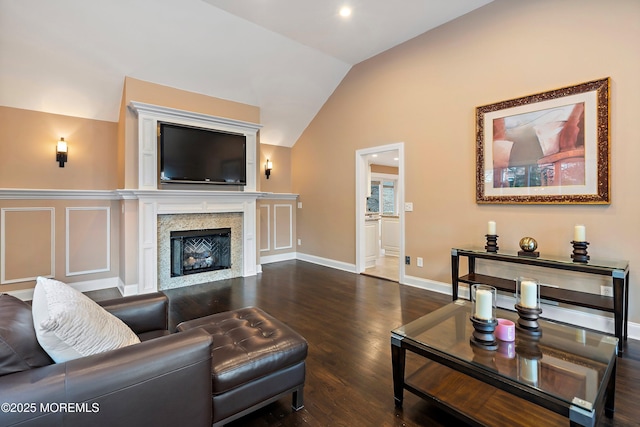 living room with lofted ceiling, a glass covered fireplace, baseboards, and wood finished floors