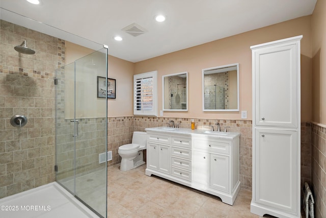 full bathroom featuring a stall shower, a sink, visible vents, and tile walls