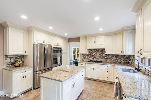 kitchen featuring stainless steel appliances, a kitchen island, a sink, decorative backsplash, and light stone countertops