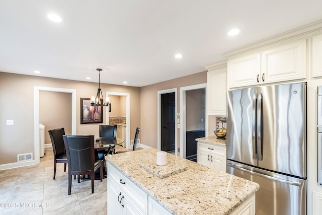 kitchen featuring recessed lighting, visible vents, light stone counters, and freestanding refrigerator