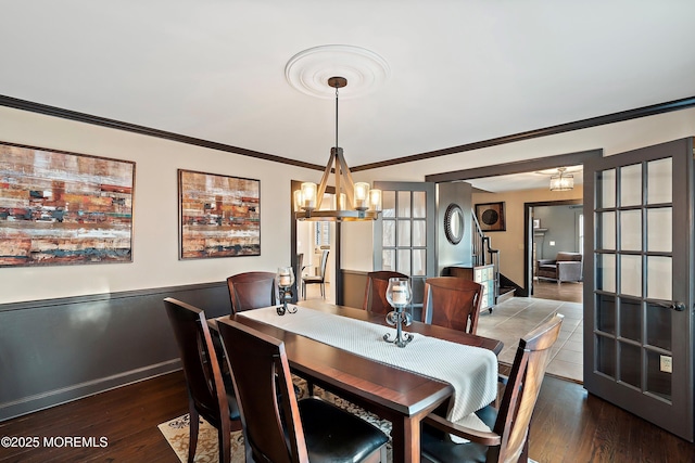 dining room with baseboards, an inviting chandelier, wood finished floors, and crown molding