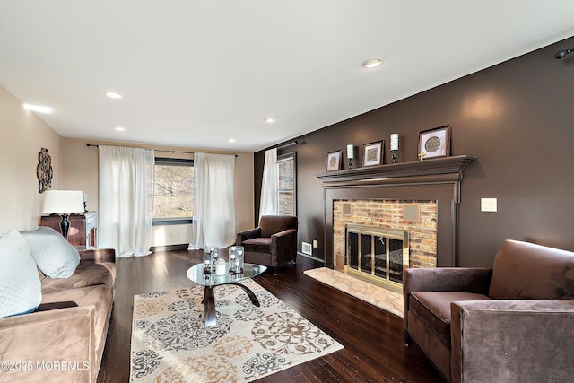 living room featuring recessed lighting, a brick fireplace, and wood finished floors