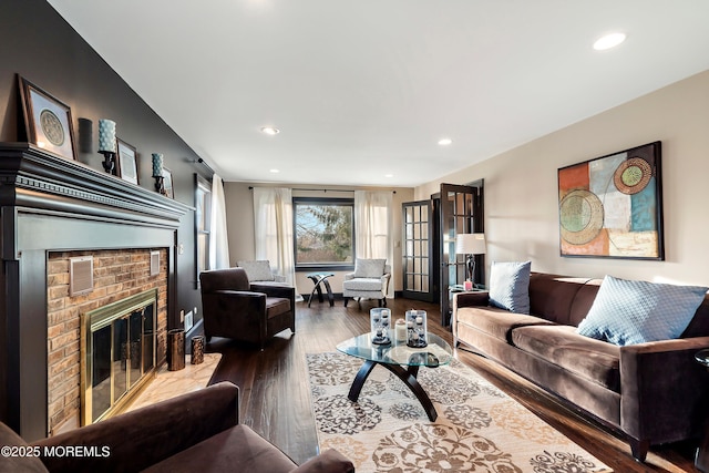 living room featuring a brick fireplace, wood finished floors, and recessed lighting