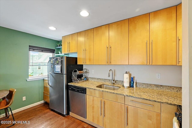 kitchen featuring wood finished floors, a sink, baseboards, appliances with stainless steel finishes, and light stone countertops