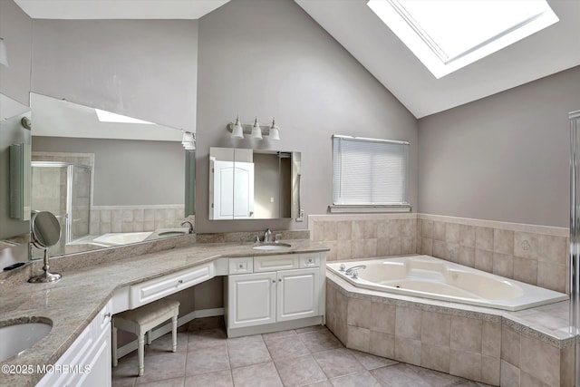 bathroom with double vanity, a skylight, tile patterned floors, a whirlpool tub, and a sink