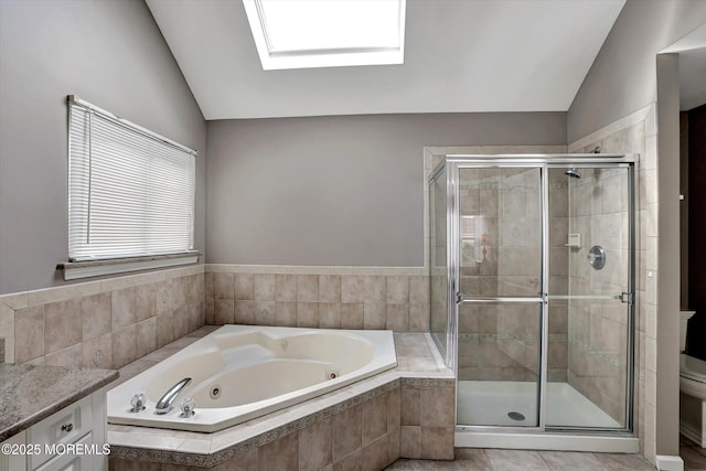 full bathroom with a stall shower, vaulted ceiling with skylight, and a tub with jets