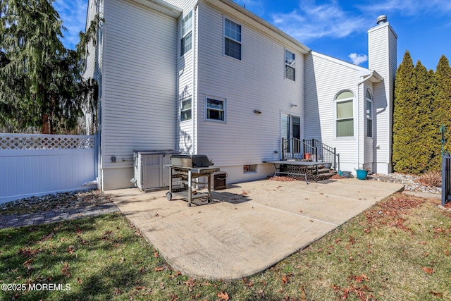 rear view of house featuring a chimney, a patio area, and fence