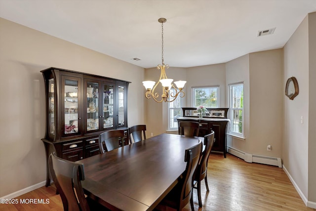 dining area with a baseboard heating unit, visible vents, and light wood finished floors