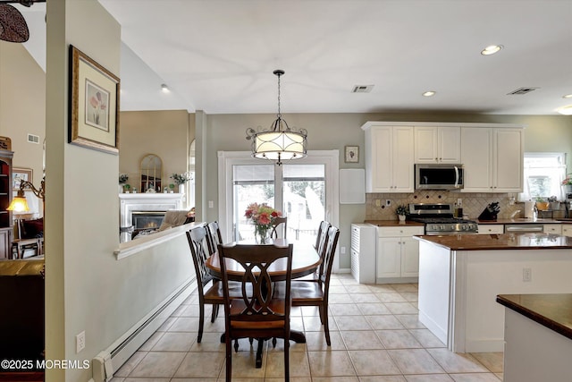 kitchen featuring stainless steel appliances, a baseboard radiator, dark countertops, visible vents, and tasteful backsplash