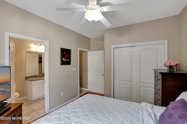 bedroom with a ceiling fan, visible vents, baseboards, a closet, and ensuite bath