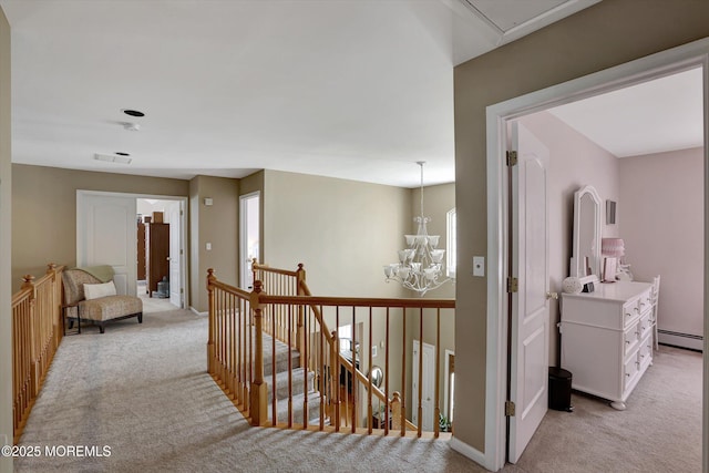 hallway with an inviting chandelier, a baseboard heating unit, attic access, light carpet, and an upstairs landing