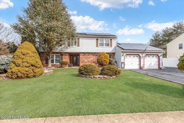 view of front of home with an attached garage, brick siding, fence, driveway, and a front yard