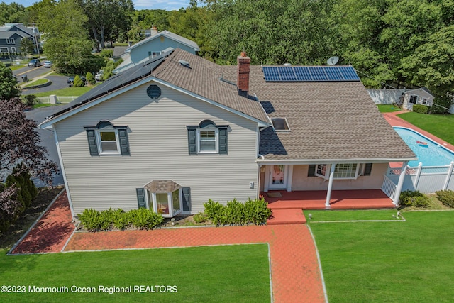 view of front of home featuring a front yard, fence, a chimney, and solar panels