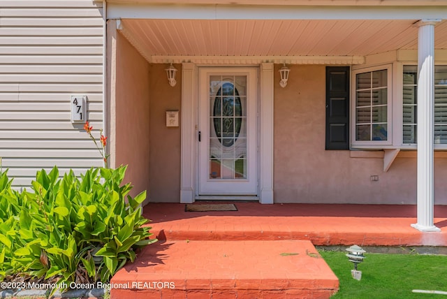 property entrance featuring covered porch and stucco siding