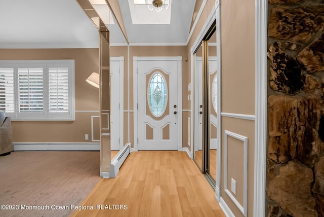 foyer entrance featuring a baseboard heating unit, ornamental molding, light wood-style flooring, and baseboards