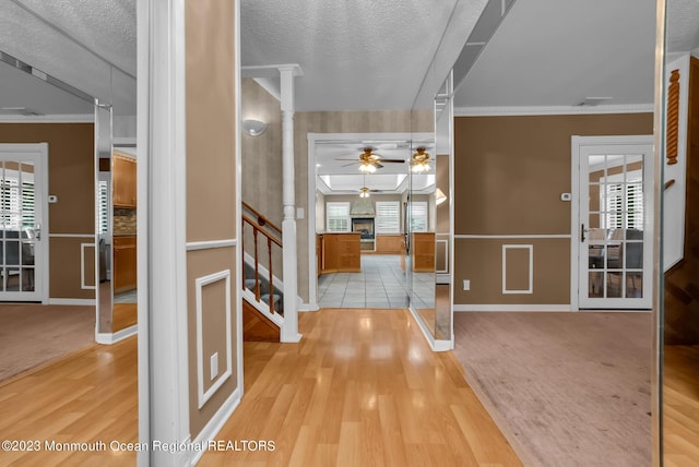 foyer with a large fireplace, light wood-style floors, stairway, decorative columns, and crown molding