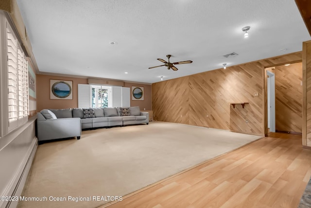 unfurnished living room featuring a textured ceiling, wooden walls, carpet floors, wood finished floors, and baseboard heating