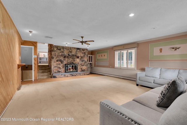 living area with ceiling fan, a baseboard heating unit, a fireplace, visible vents, and carpet