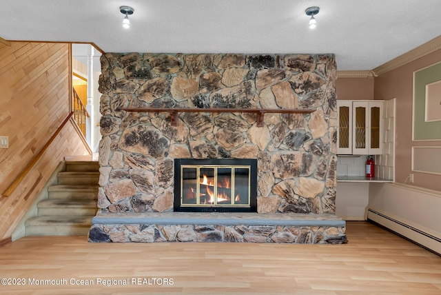 room details featuring a baseboard radiator, a fireplace, a fire extinguisher, wood finished floors, and ornamental molding