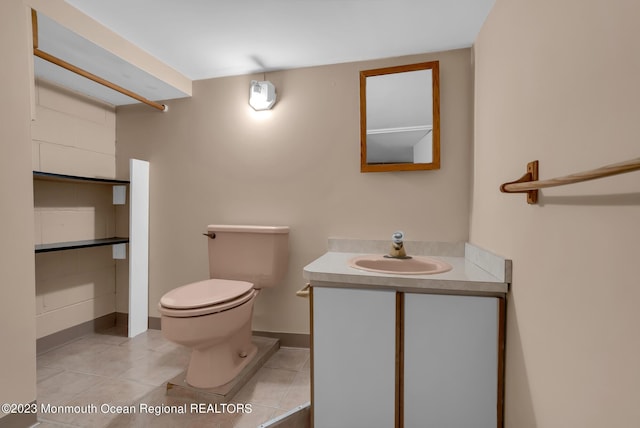 half bath featuring tile patterned flooring, baseboards, vanity, and toilet