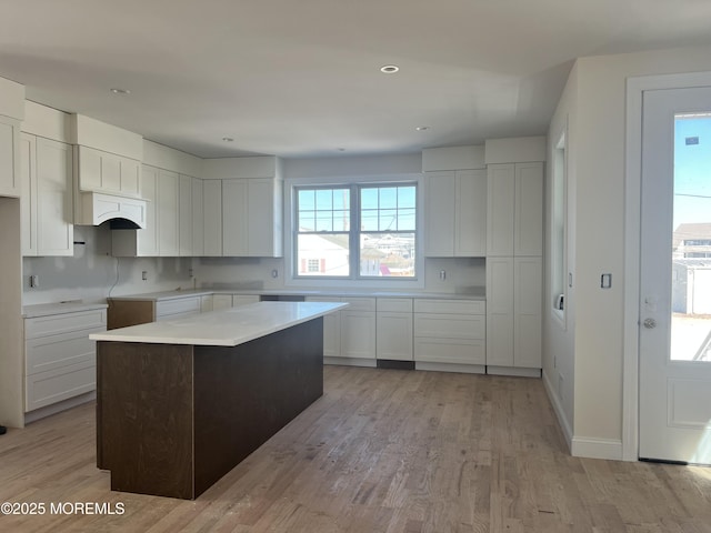 kitchen with light wood-style flooring, white cabinetry, and a kitchen island