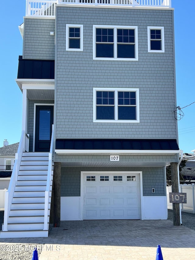 view of front of home with stairway, a standing seam roof, a garage, decorative driveway, and metal roof