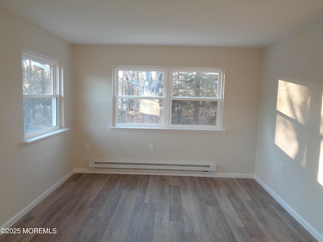 empty room with a baseboard heating unit, wood finished floors, and baseboards