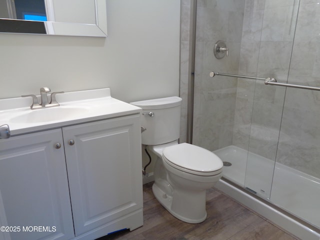 bathroom featuring toilet, a shower stall, wood finished floors, and vanity